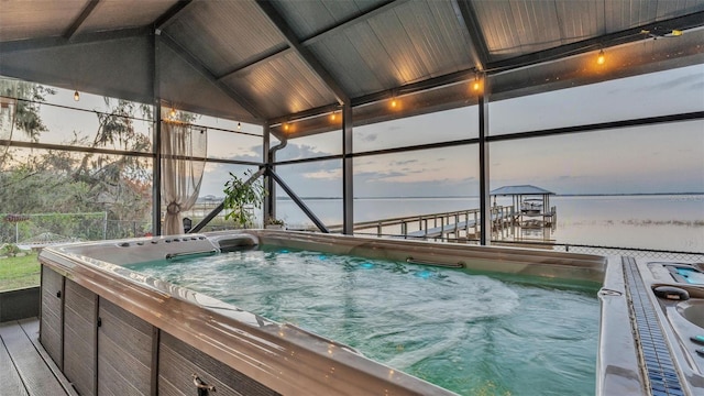 pool at dusk featuring a hot tub