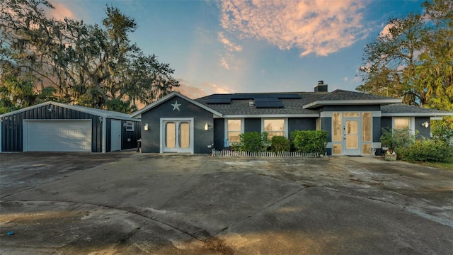 ranch-style home with french doors, a garage, an outdoor structure, and solar panels