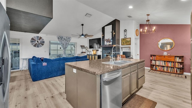 kitchen with lofted ceiling, pendant lighting, light hardwood / wood-style flooring, a center island with sink, and ceiling fan with notable chandelier