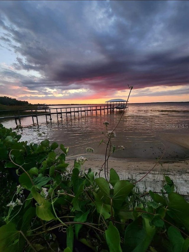 view of dock with a water view and a beach view