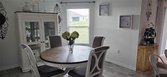 dining area featuring a textured wall and baseboards