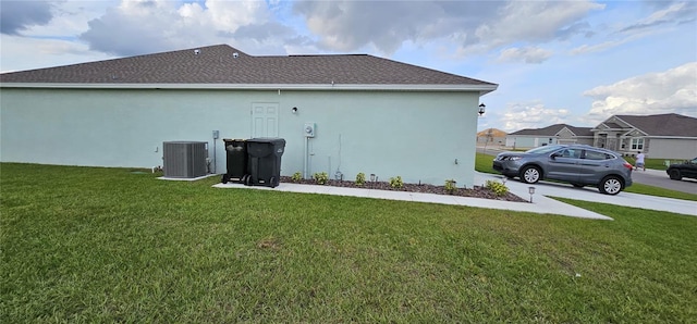 view of side of home with cooling unit, a yard, and stucco siding