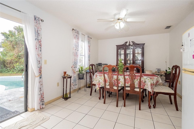 dining space featuring a textured ceiling, ceiling fan, and light tile patterned flooring