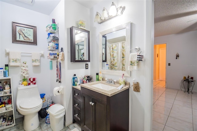 bathroom featuring toilet, vanity, tile patterned flooring, and a textured ceiling