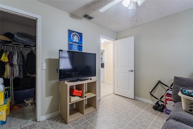 living room with ceiling fan and a textured ceiling