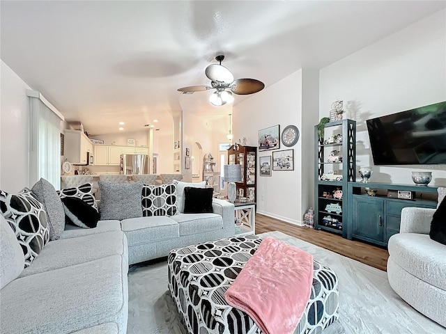 living room featuring ceiling fan, light hardwood / wood-style floors, and vaulted ceiling