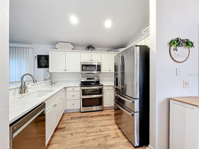 kitchen featuring stainless steel appliances, white cabinetry, light hardwood / wood-style floors, and sink