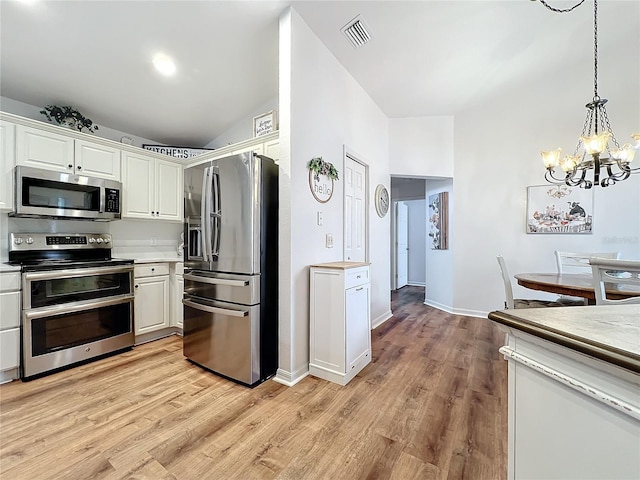 kitchen with light hardwood / wood-style floors, white cabinetry, stainless steel appliances, and a chandelier