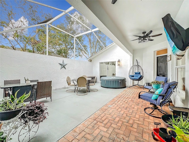 view of patio with glass enclosure, ceiling fan, and a hot tub