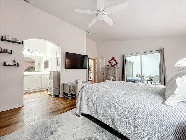 bedroom with ceiling fan, light wood-type flooring, connected bathroom, and vaulted ceiling