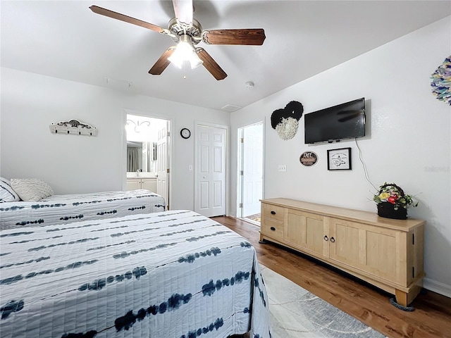 bedroom with ensuite bath, ceiling fan, and dark hardwood / wood-style flooring