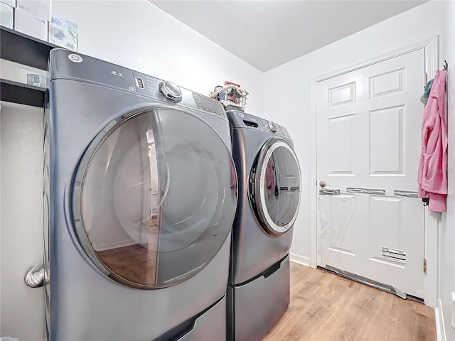 laundry room featuring washer and clothes dryer and light hardwood / wood-style flooring