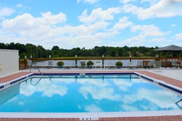 view of swimming pool featuring a gazebo, a patio area, and a water view