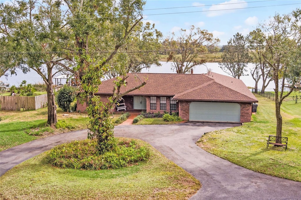 ranch-style house with a front yard, a garage, and a water view