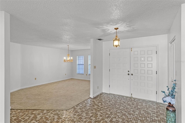 foyer with a textured ceiling, a chandelier, and carpet