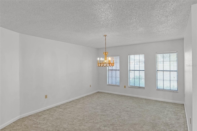 unfurnished room with a notable chandelier, light colored carpet, and a textured ceiling