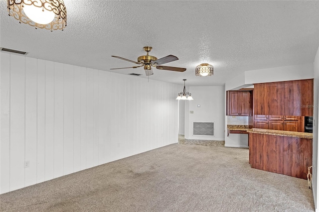 unfurnished living room featuring a textured ceiling, wood walls, and light carpet