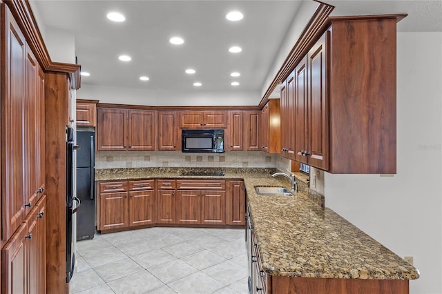 kitchen featuring sink, light tile patterned flooring, decorative backsplash, dark stone counters, and black appliances