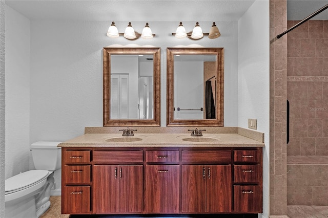 bathroom with toilet, tile patterned floors, tiled shower, and vanity