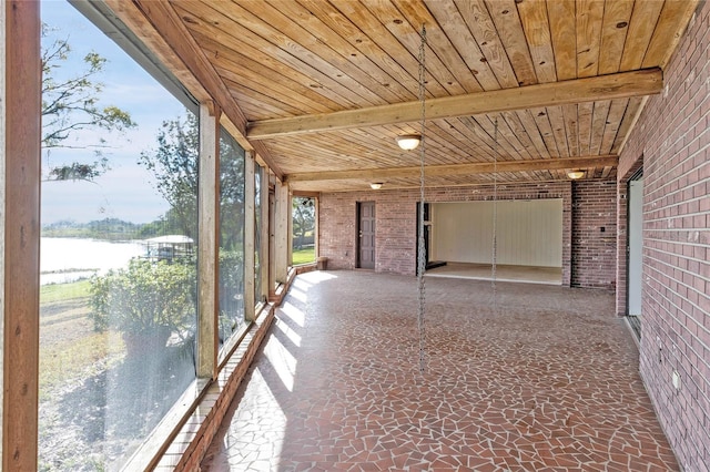 unfurnished sunroom featuring wood ceiling, a healthy amount of sunlight, and a water view