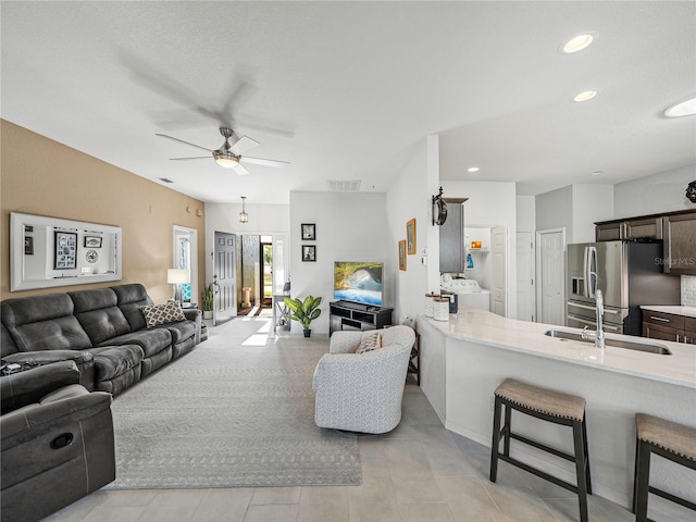 living room featuring separate washer and dryer, ceiling fan, and sink