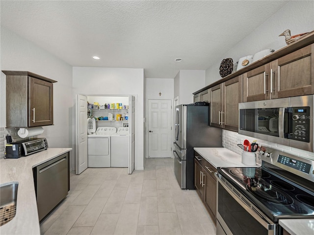 kitchen with washer and clothes dryer, backsplash, a textured ceiling, appliances with stainless steel finishes, and dark brown cabinetry