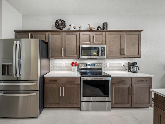 kitchen featuring backsplash, dark brown cabinets, light tile patterned floors, and stainless steel appliances