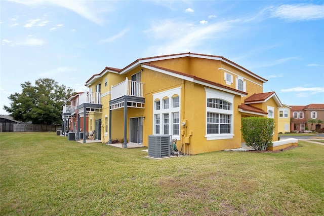 back of house with a balcony, central air condition unit, and a yard