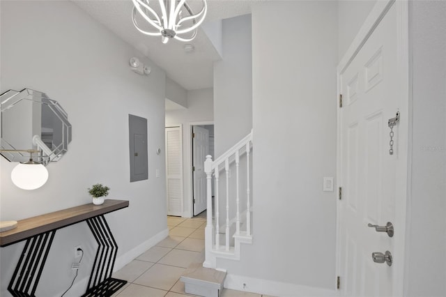 tiled entryway with electric panel, a textured ceiling, and an inviting chandelier