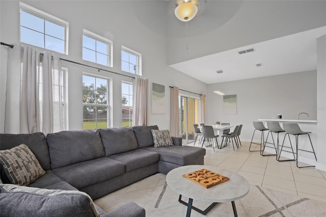 living room with ceiling fan, a towering ceiling, and light tile patterned flooring