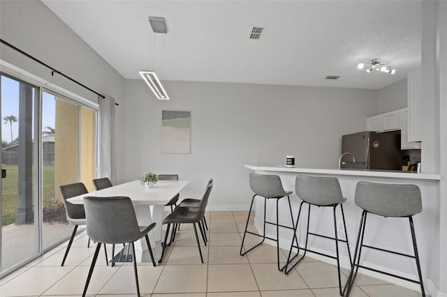 dining room with sink, a textured ceiling, rail lighting, and light tile patterned flooring