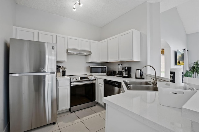 kitchen featuring sink, stainless steel appliances, light tile patterned floors, a textured ceiling, and white cabinets