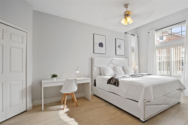 bedroom featuring a textured ceiling, ceiling fan, light hardwood / wood-style flooring, and a closet