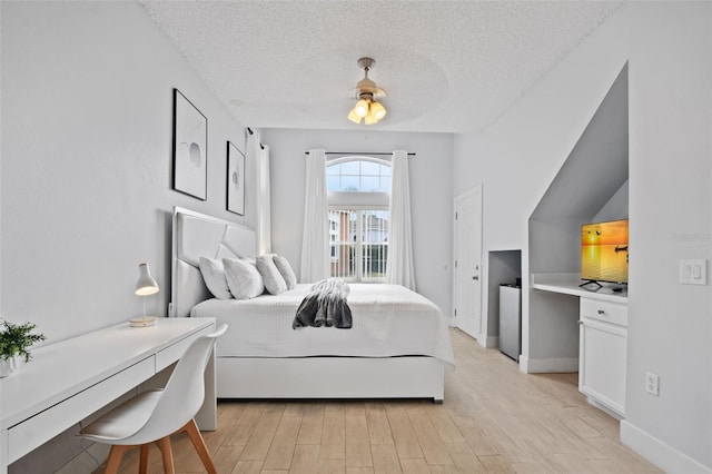 bedroom featuring a textured ceiling, light wood-type flooring, and ceiling fan