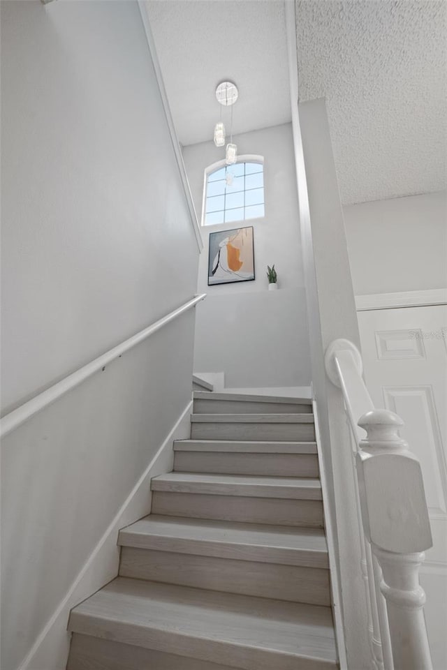 staircase featuring a textured ceiling