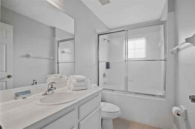 full bathroom featuring a textured ceiling, vanity, toilet, and enclosed tub / shower combo