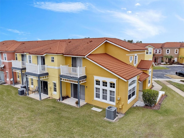 rear view of house featuring a lawn, central AC, and a balcony