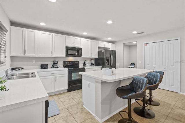 kitchen with a kitchen island, sink, black appliances, white cabinetry, and a breakfast bar area