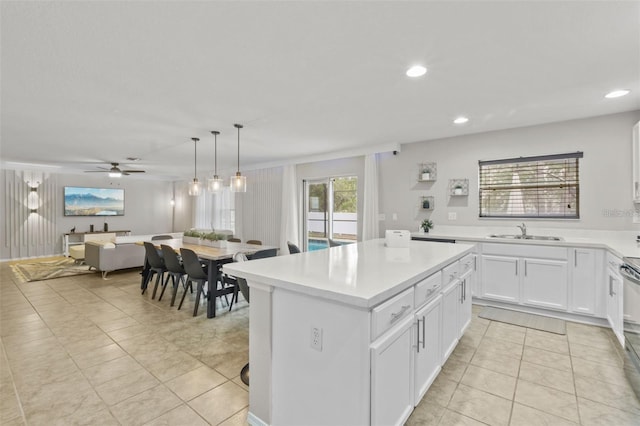 kitchen featuring a center island, white cabinets, sink, hanging light fixtures, and ceiling fan