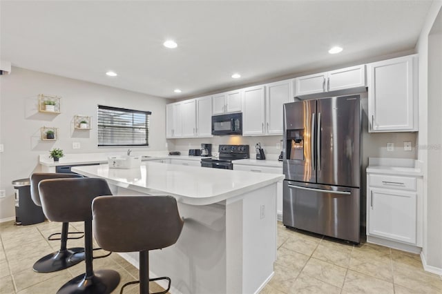 kitchen with a kitchen bar, white cabinetry, a center island, and black appliances