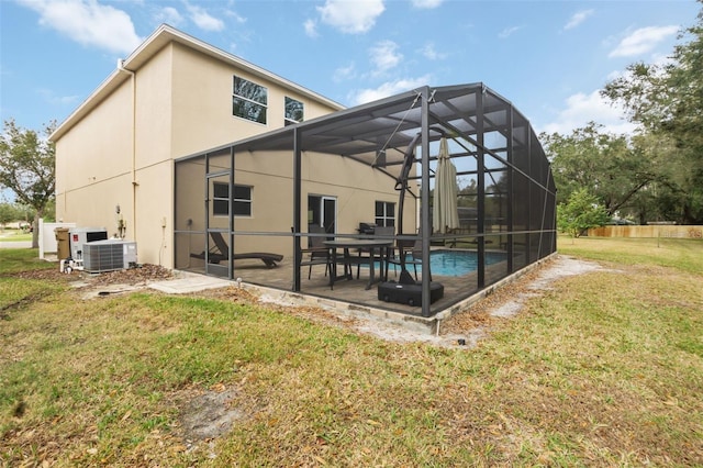 back of house featuring a yard, a lanai, central air condition unit, a fenced in pool, and a patio area