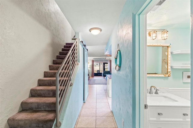 stairs featuring tile patterned floors and sink