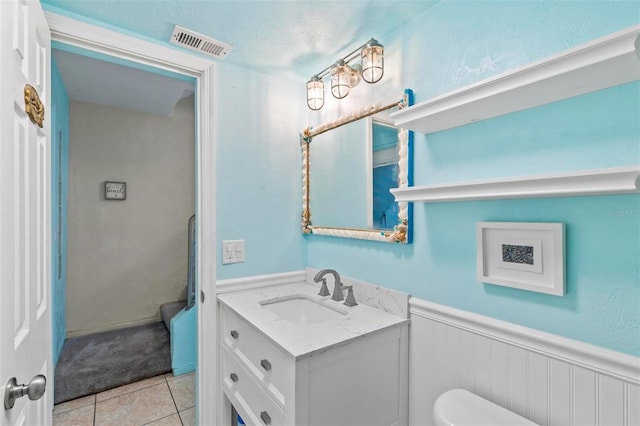 bathroom with tile patterned floors, vanity, a textured ceiling, and toilet