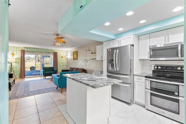 kitchen with white cabinets, ceiling fan, light stone countertops, and stainless steel appliances