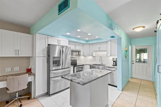 kitchen featuring light stone counters, stainless steel appliances, white cabinetry, and sink