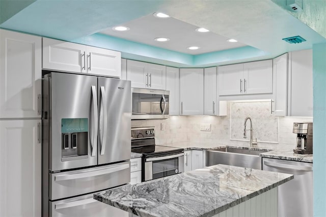 kitchen with a raised ceiling, white cabinetry, sink, and appliances with stainless steel finishes