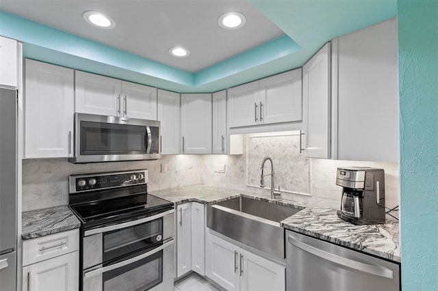 kitchen featuring light stone countertops, tasteful backsplash, stainless steel appliances, sink, and white cabinets