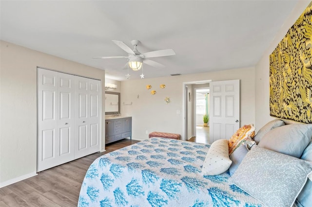 bedroom featuring ceiling fan, ensuite bath, wood-type flooring, and a closet