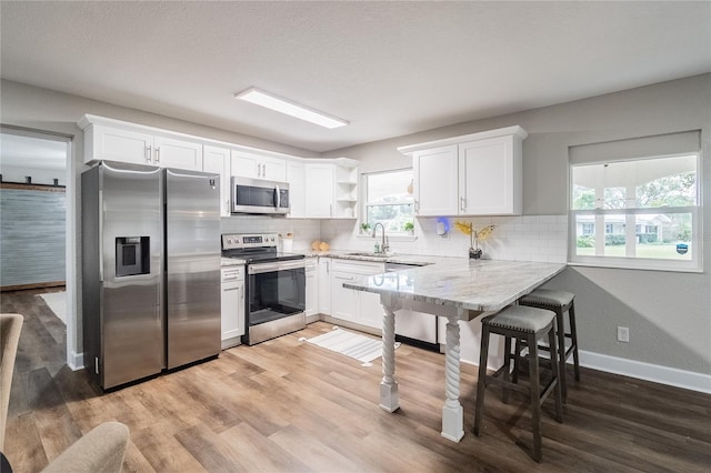 kitchen featuring white cabinetry, sink, backsplash, and stainless steel appliances