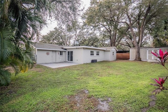 back of property with central AC unit, a patio, and a yard